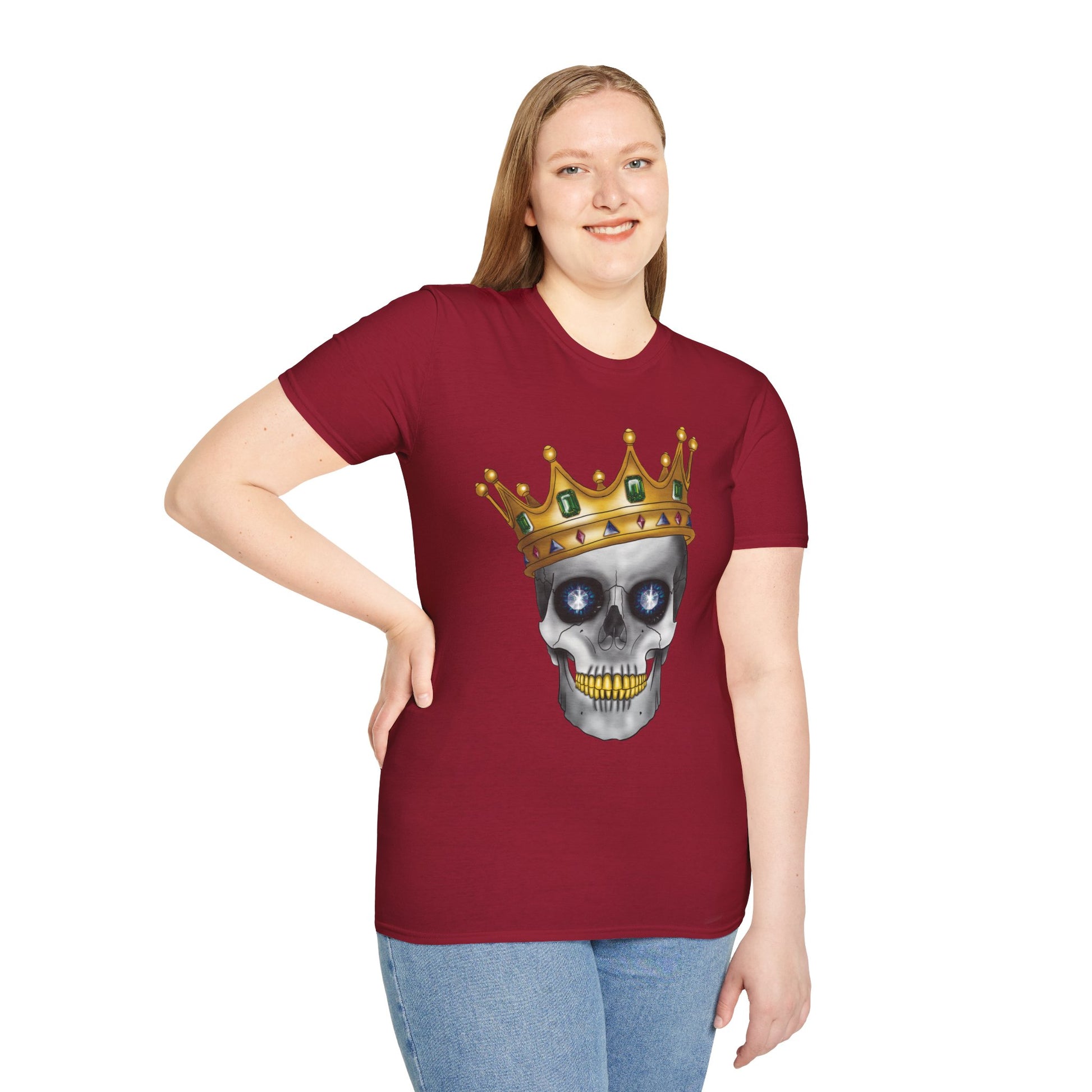 Woman wearing a red t-shirt featuring an anatomical skull wearing an ornate crown, with gold teeth, large sapphire gemstones in the eye sockets, and emeralds and rubies decorating the crown.