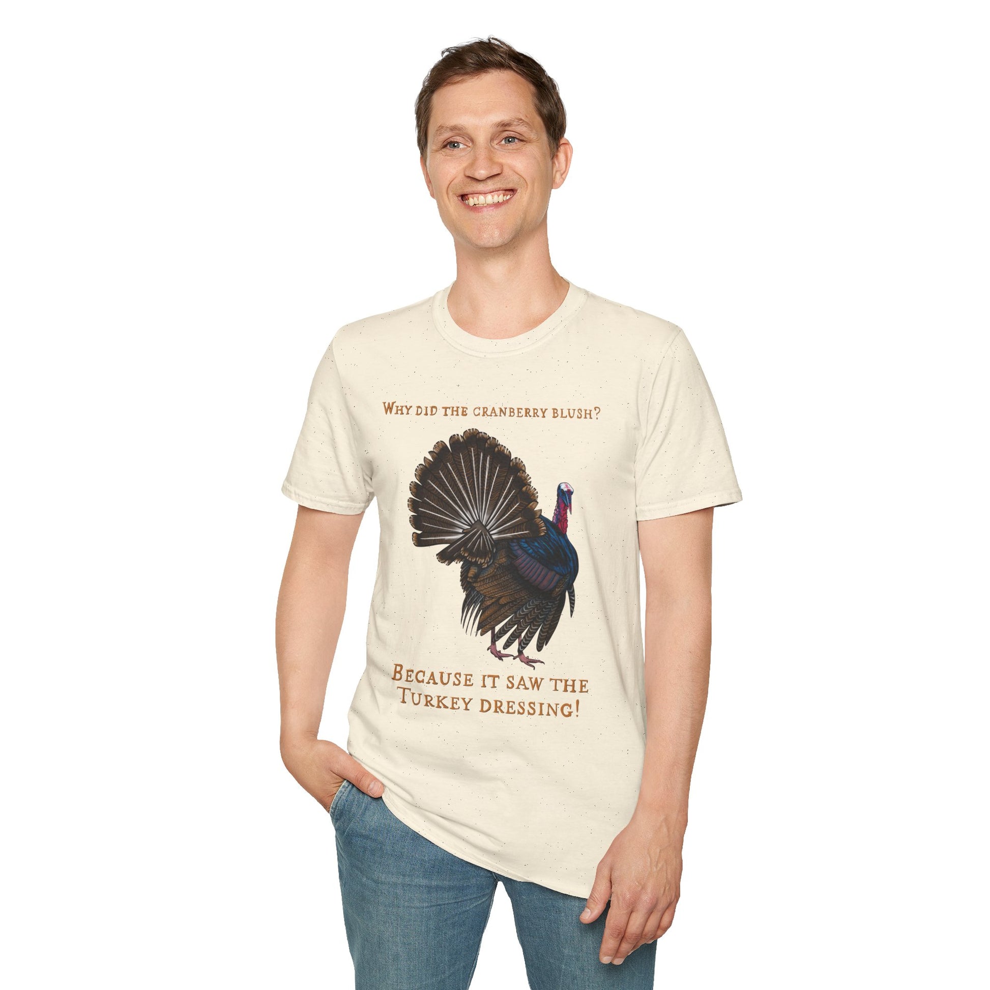 Man wearing a beige Thanksgiving t-shirt featuring a picture of a turkey and the text 'Why did the cranberry blush? Because it saw the turkey dressing!