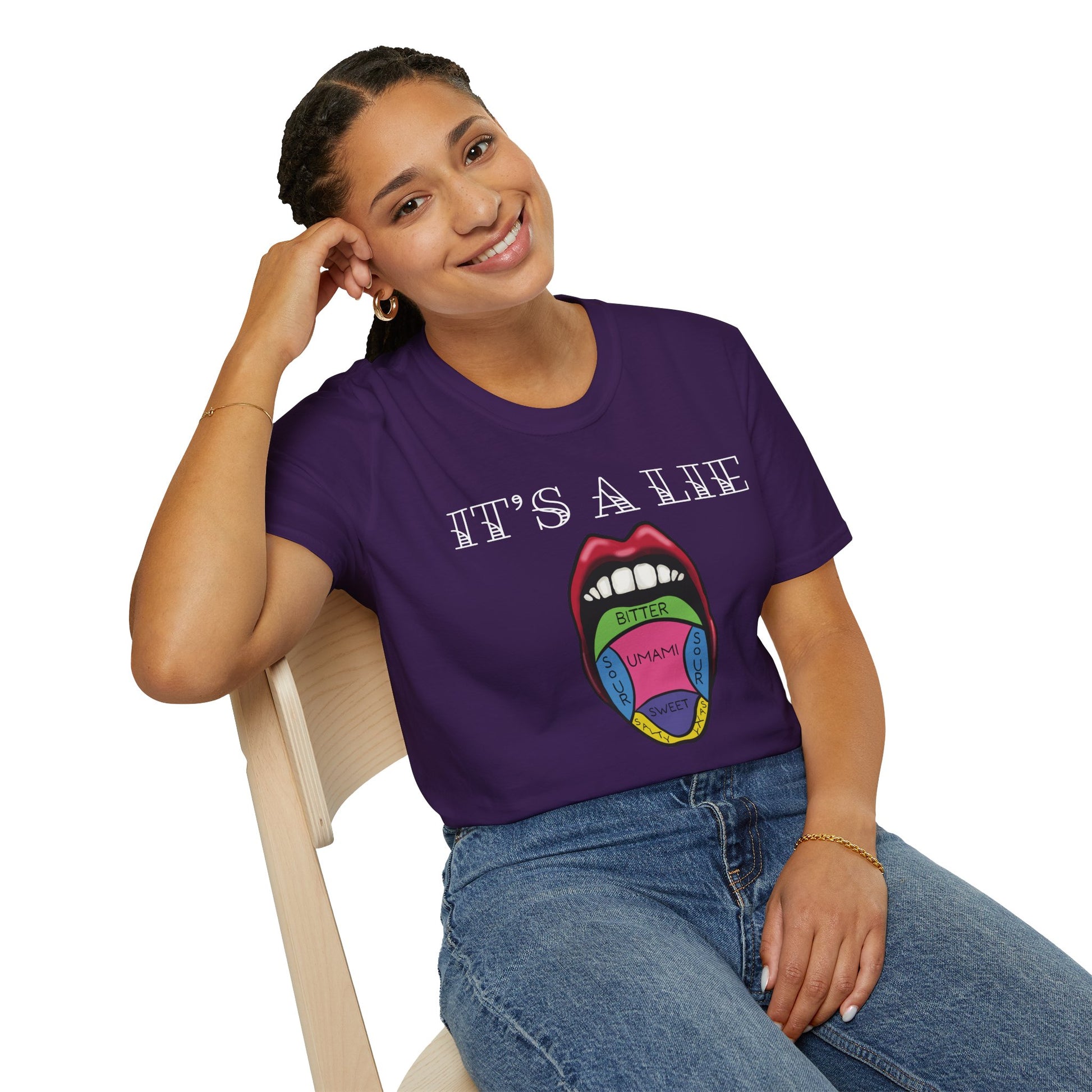Woman wearing a purple short-sleeve unisex t-shirt featuring a classic tongue taste map with the words “It’s a lie” boldly above it—busting the myth that different parts of your tongue taste different things. Sweet, salty, sour, bitter? Taste buds don’t discriminate!