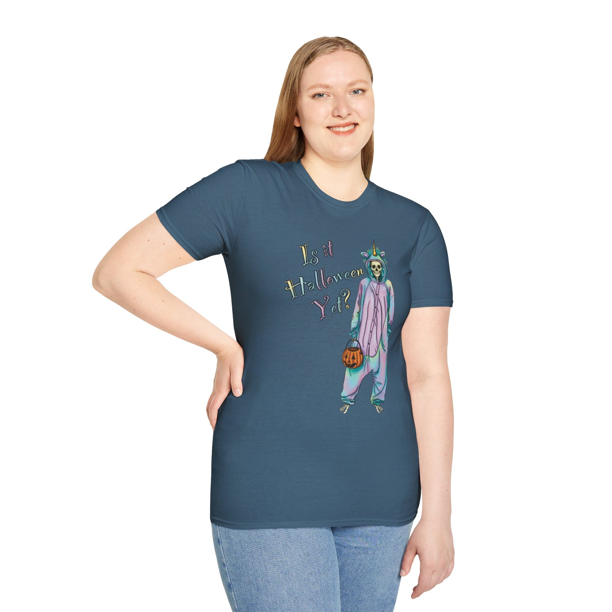 Woman wearing a blue t-shirt featuring a drawing of a skeleton in a unicorn costume onesie, with the phrase 'Is it Halloween yet?' printed on it.
