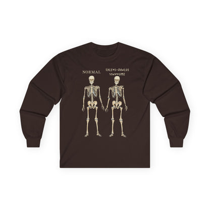 A brown long sleeve shirt with two skeletons side by side—one labeled "normal," the other "Ehlers-Danlos Syndrome"—visually showcasing the effects of EDS with a clever, anatomy-inspired twist.