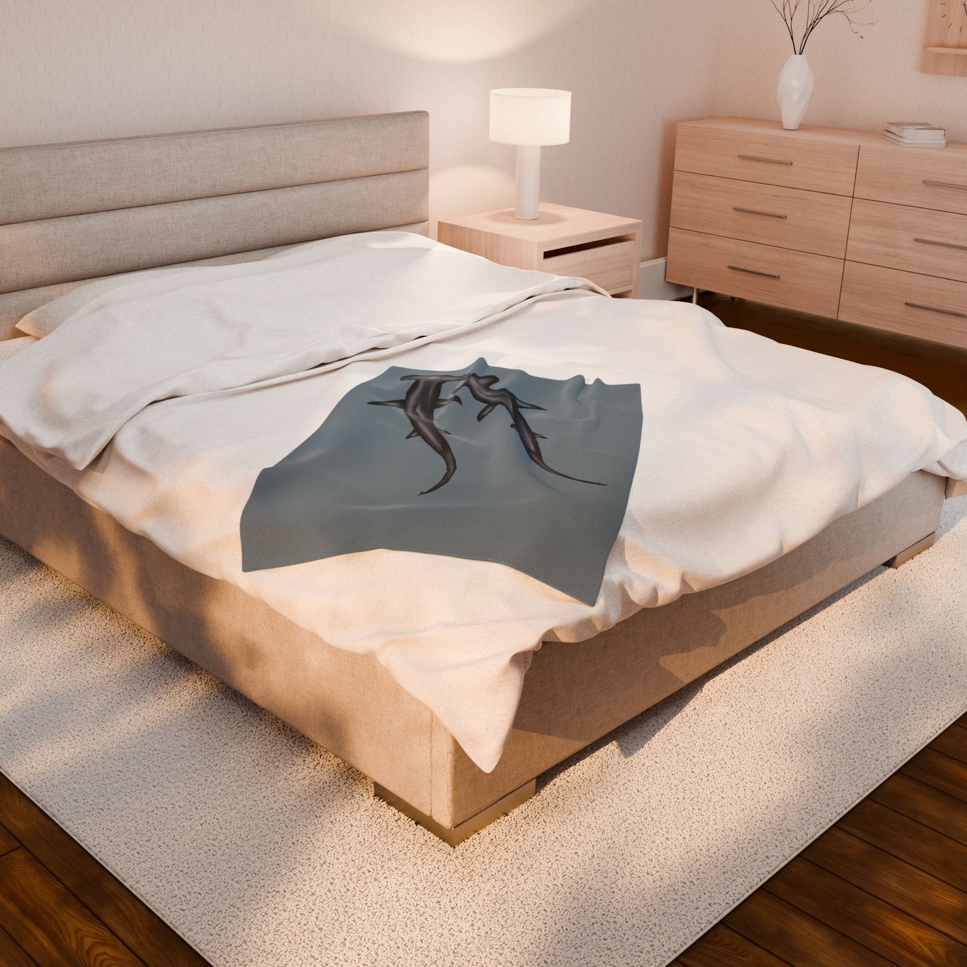 A small blue-grey velveteen plush blanket featuring two hammerhead sharks gliding through the fabric like it's their personal ocean—perfect for wrapping yourself in comfort with a side of bite. Shown on a queen size bed.